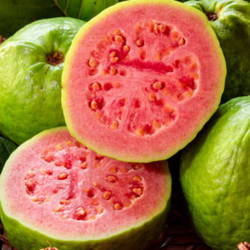 Fresh pink guava fruit with one half sliced open showing the pink flesh and seeds.