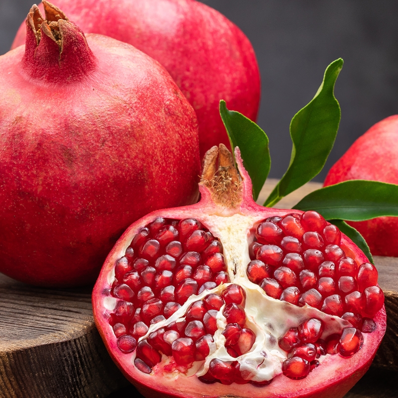 Fresh pomegranate with one half cut open showing bright red seeds.
