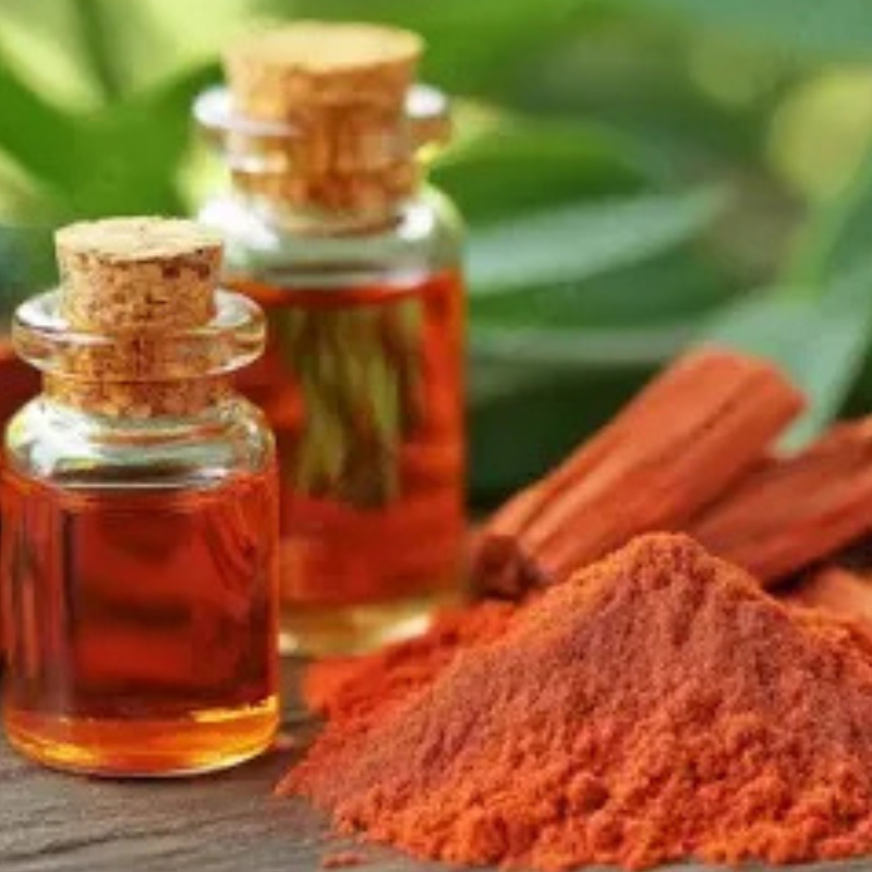 Manjistha roots and reddish herbal powder in a wooden bowl on a white background.