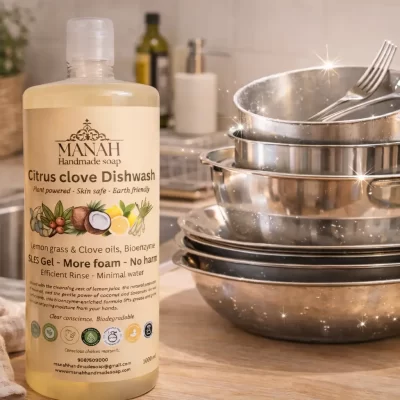 Manah Citrus Clove Dishwash Liquid bottle placed beside sparkling cleaned utensils in a tidy kitchen setup